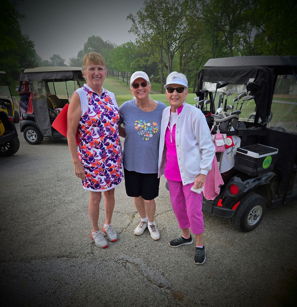 3 ladies in front of golf carts