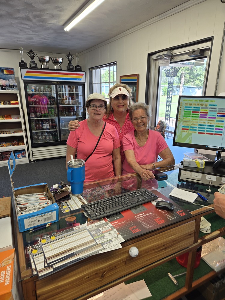 3 ladies with pink blouses standing in front of counter