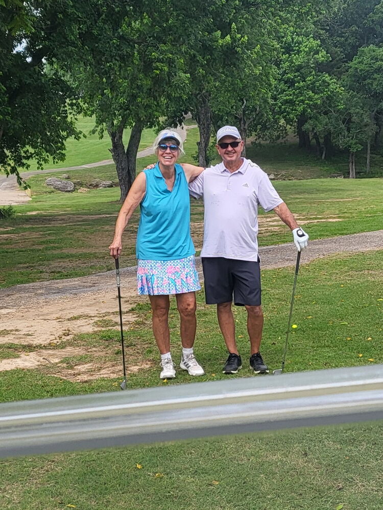 Woman and Man standing on golf course holding golf clubs.