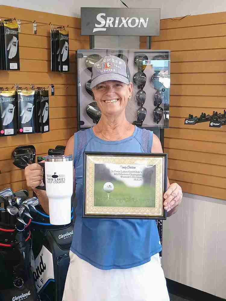 Woman in golf shop holding certificate and thermal mug
