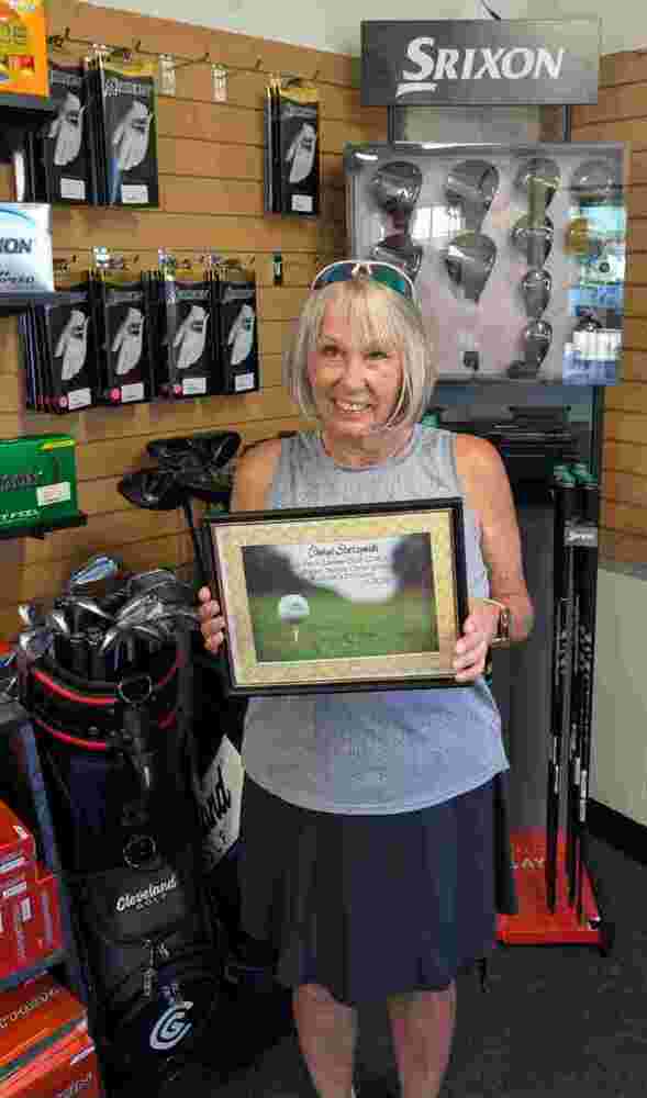Woman holding certificate standing in golf shop