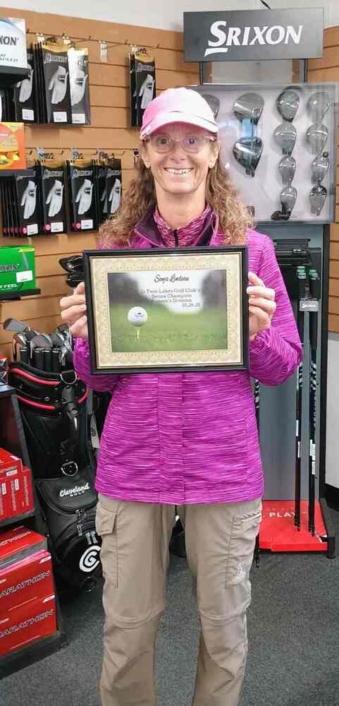 Lady with long hair holding certificate in golf shop